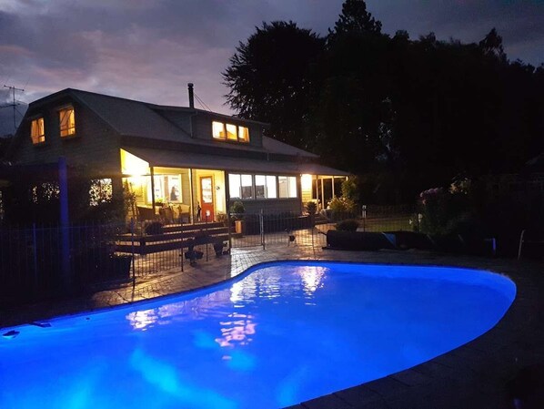 Una casa con piscina al anochecer.