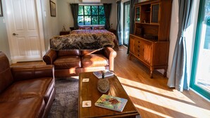 Een ruime woonkamer met lederen meubels, een houten salontafel en een groot raam met gordijnen.