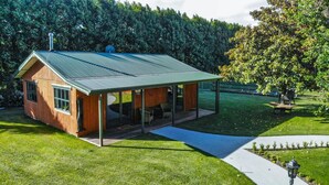 Een klein houten huisje met een metalen dak en een overdekte veranda.