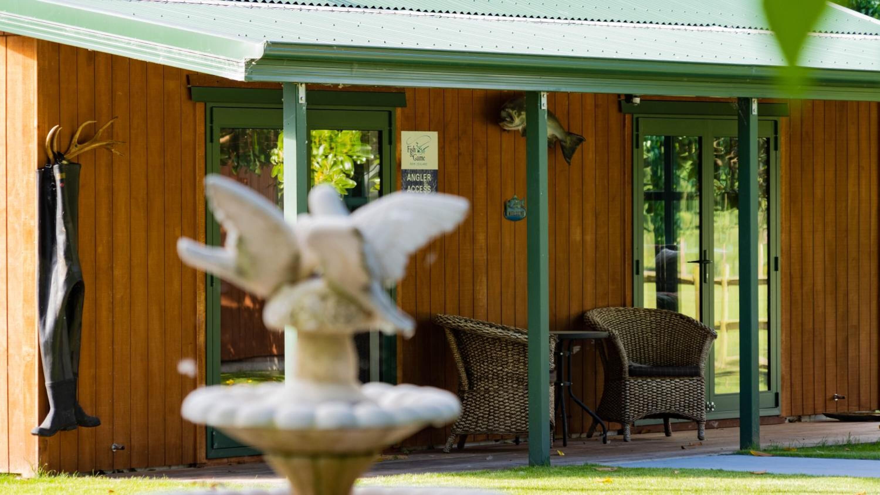 A wooden building with a covered porch, a sign indicating 'Angler Access', and outdoor seating.