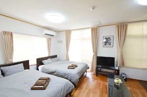 A hotel room with two beds, a TV, and a small table with a vase of flowers. - Chateau TIIDA 1F (Naha)