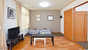 Een woonkamer met een televisie, bank en houten deuren.