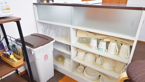 Een keuken met een wit kastje vol servies en keukengerei.