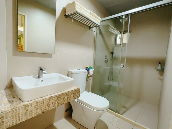 A bathroom with a white sink, toilet, and glass shower enclosure.