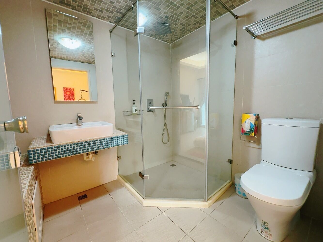 A bathroom with a glass-enclosed shower, a white sink, and a toilet.