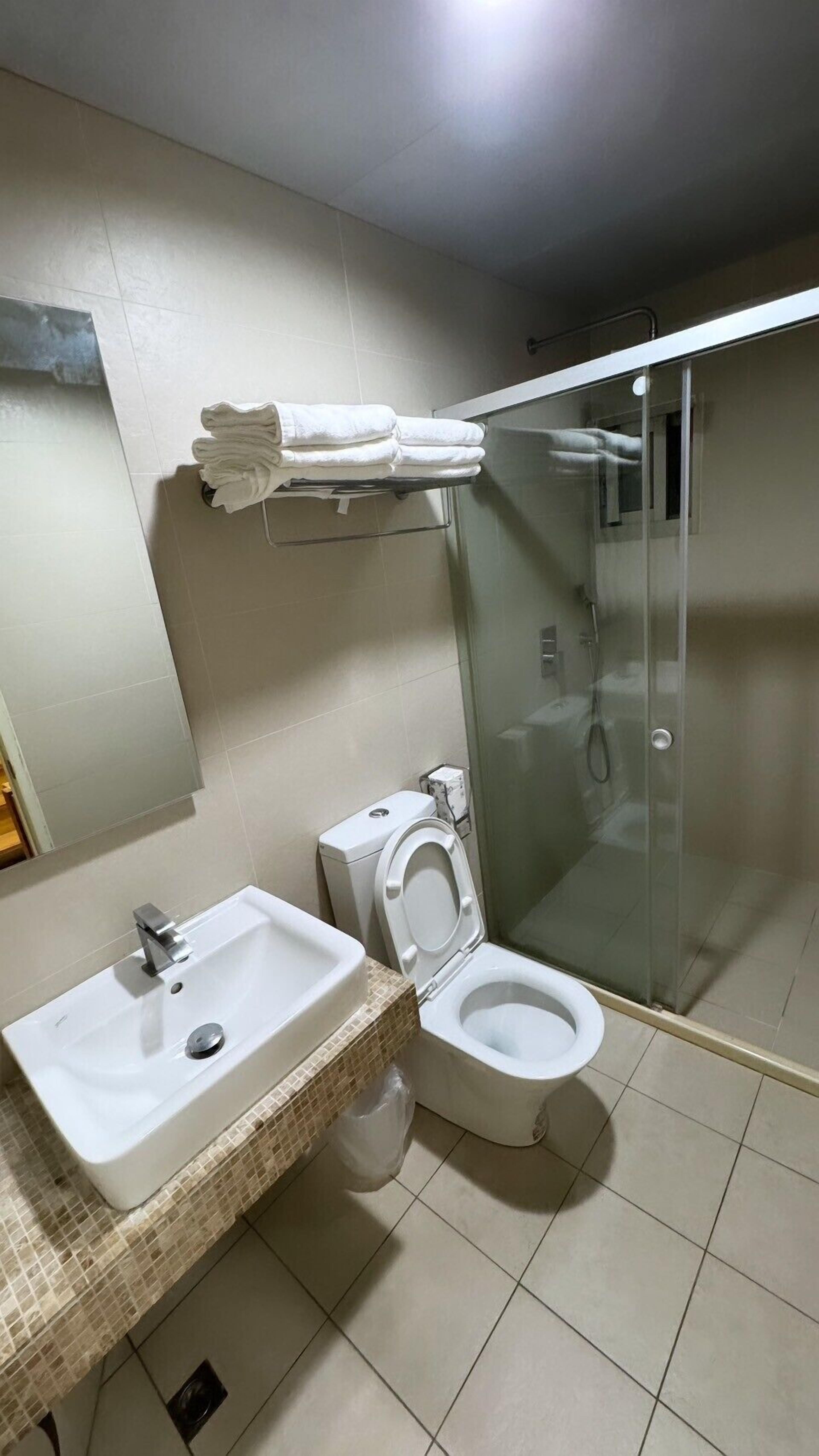 Un baño con lavamanos, inodoro y cabina de ducha de vidrio.