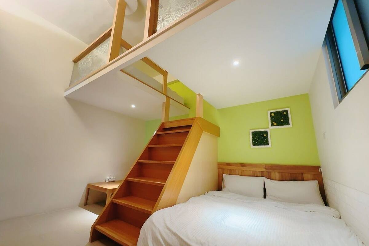 Un dormitorio con cama, una escalera de madera y una mesita de noche pequeña.