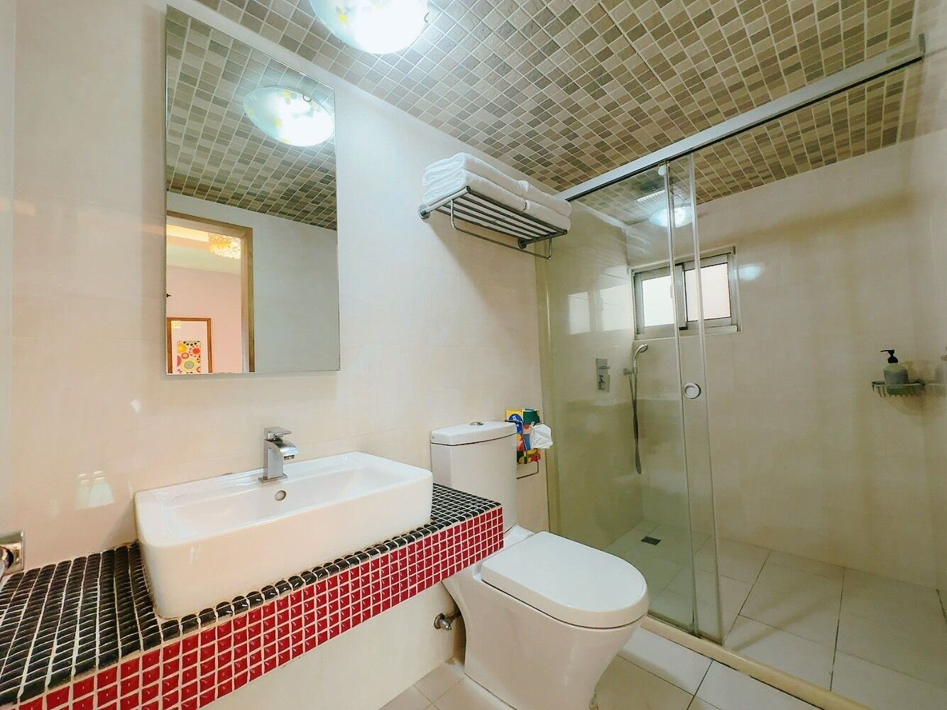 A bathroom with a white sink, a toilet, a glass shower enclosure, and a tiled backsplash.