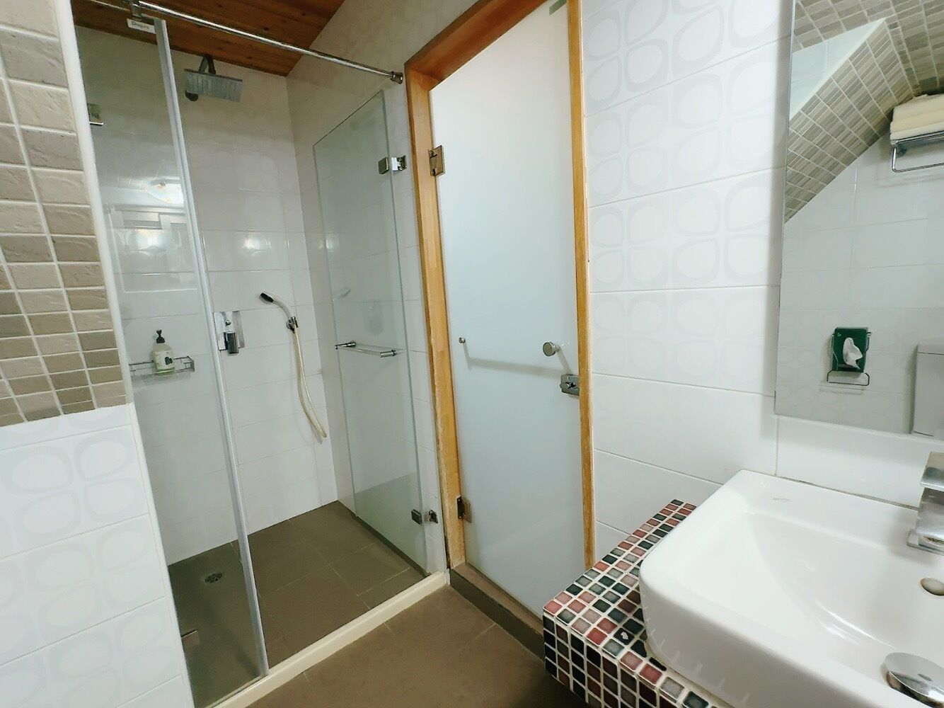 A bathroom with a glass-enclosed shower, a sink, and a mirror.