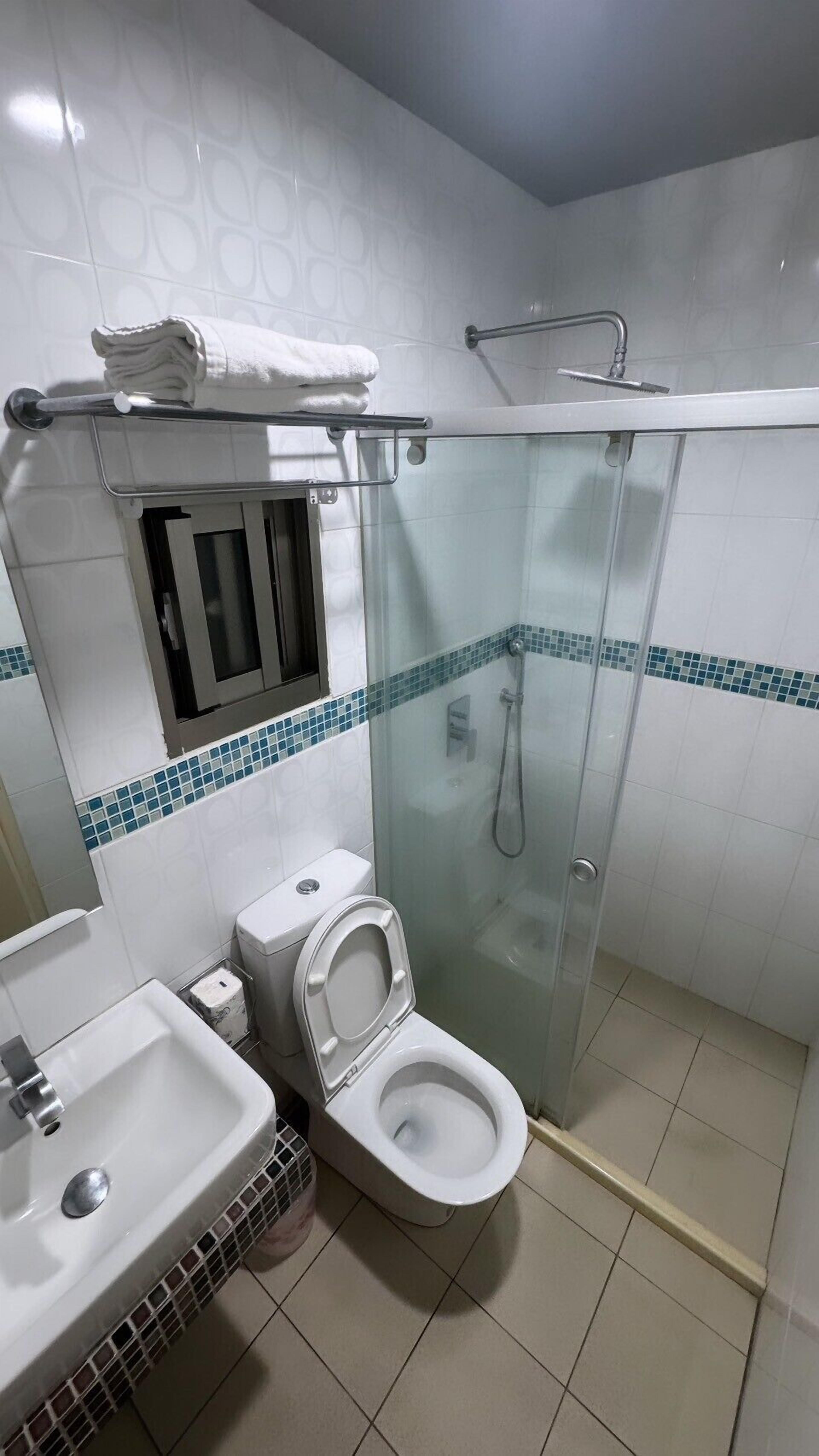 Un baño con inodoro, lavamanos y ducha con mampara de vidrio.
