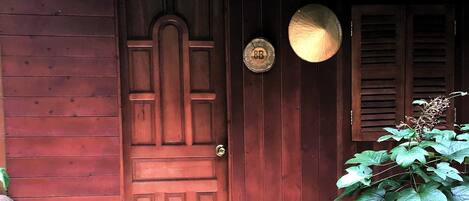 A wooden door with a circular plaque, a hanging light fixture, and a potted plant.