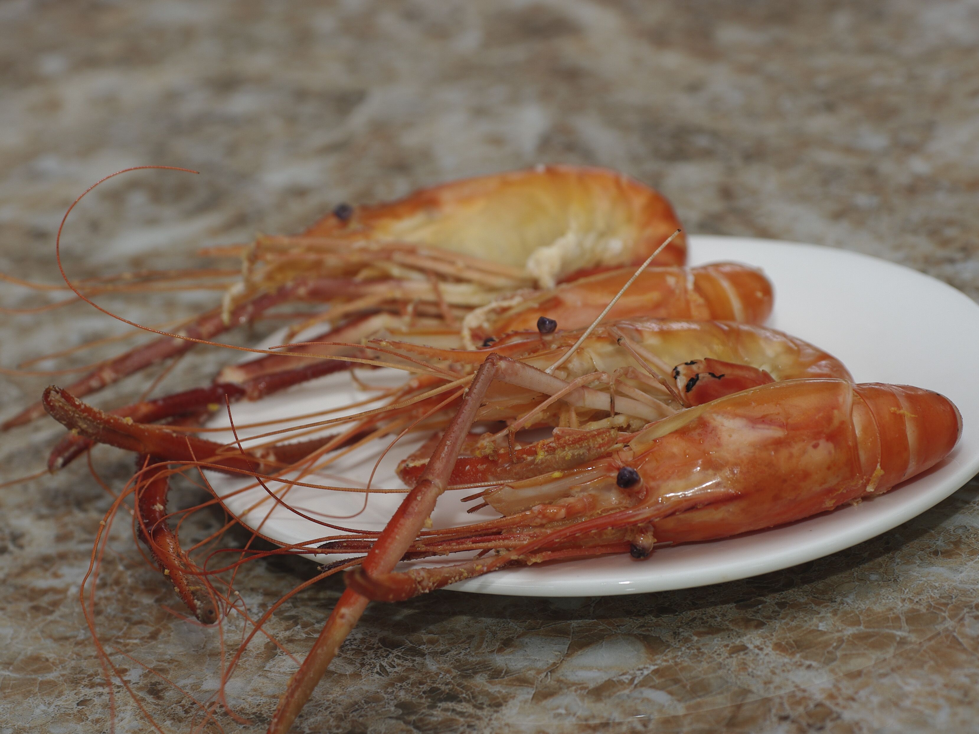A plate of cooked shrimp on a white plate.