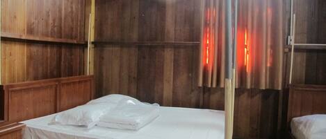 A wooden room with a single bed, wooden walls, and a curtain.