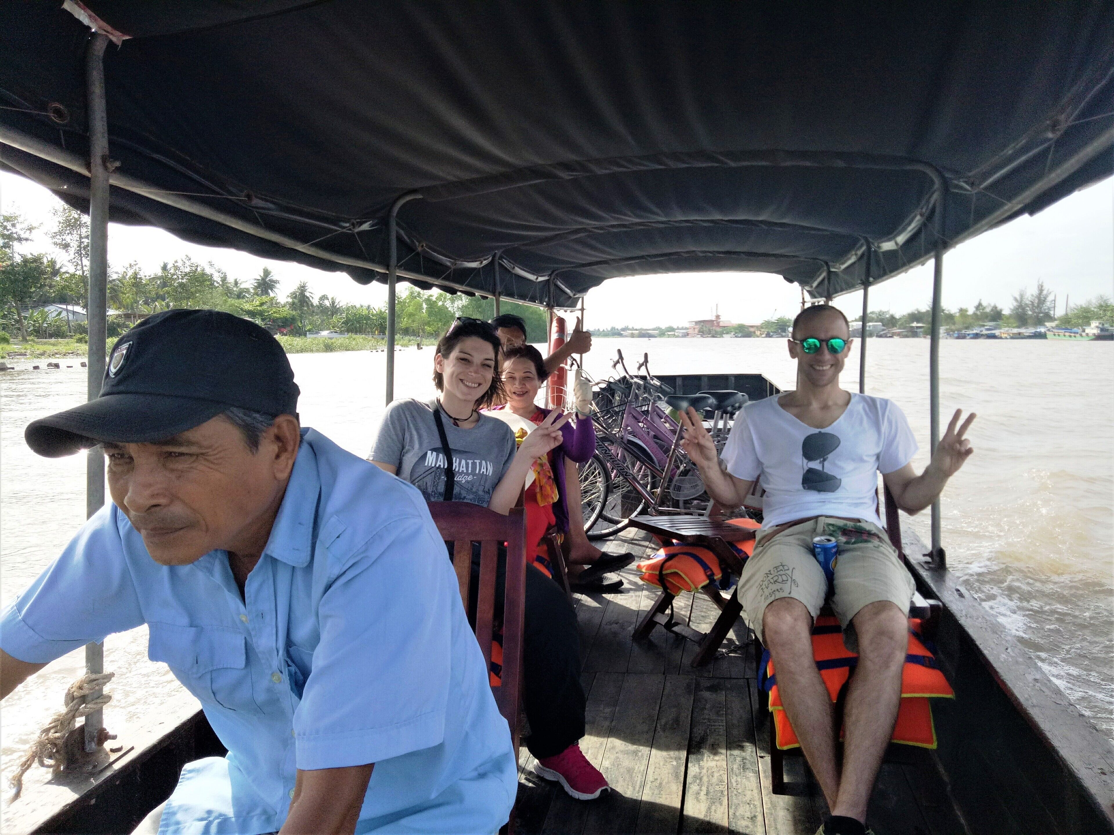 A boat with a covered top, passengers, and bicycles.
