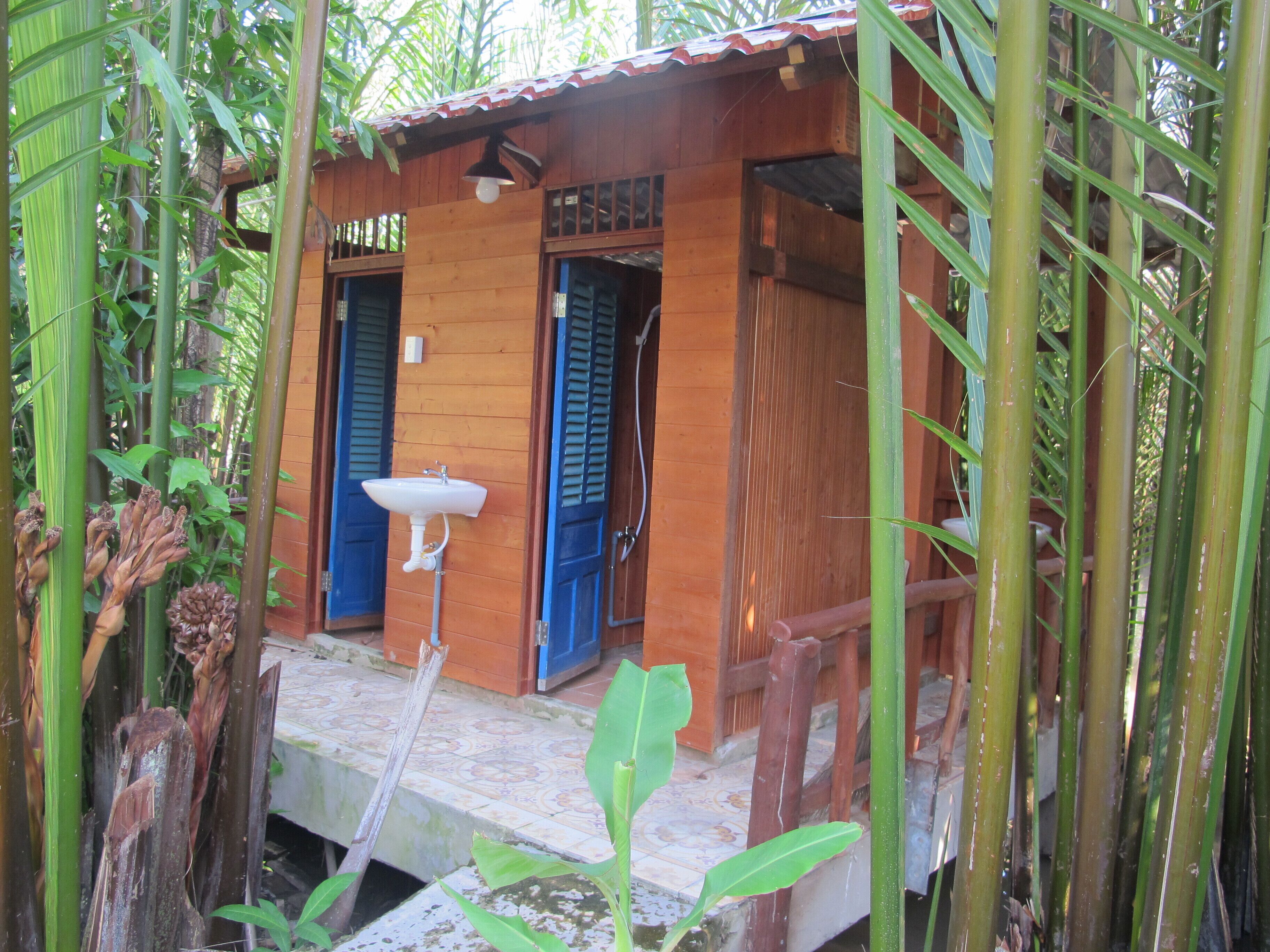 Una baita in legno con un portico in tegole, un lavandino e persiane blu.