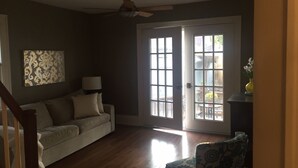 Un salon avec un canapé, un fauteuil, une lampe et un ventilateur de plafond.
