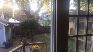 Une terrasse en bois avec une table et des chaises, entourée d’une clôture en bois et d’un grand arbre.