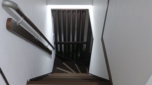 A modern staircase with wooden steps and a black handrail. - Funhouse Katsuragawa (Kyoto)