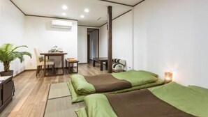 A room with two beds, a desk, a chair, a potted plant, and a bedside table with a lamp. - Funhouse Katsuragawa (Kyoto)