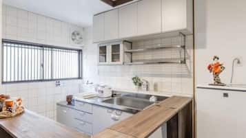 A modern kitchen with white cabinets, a wooden countertop, a stainless steel sink, and a window with blinds.
