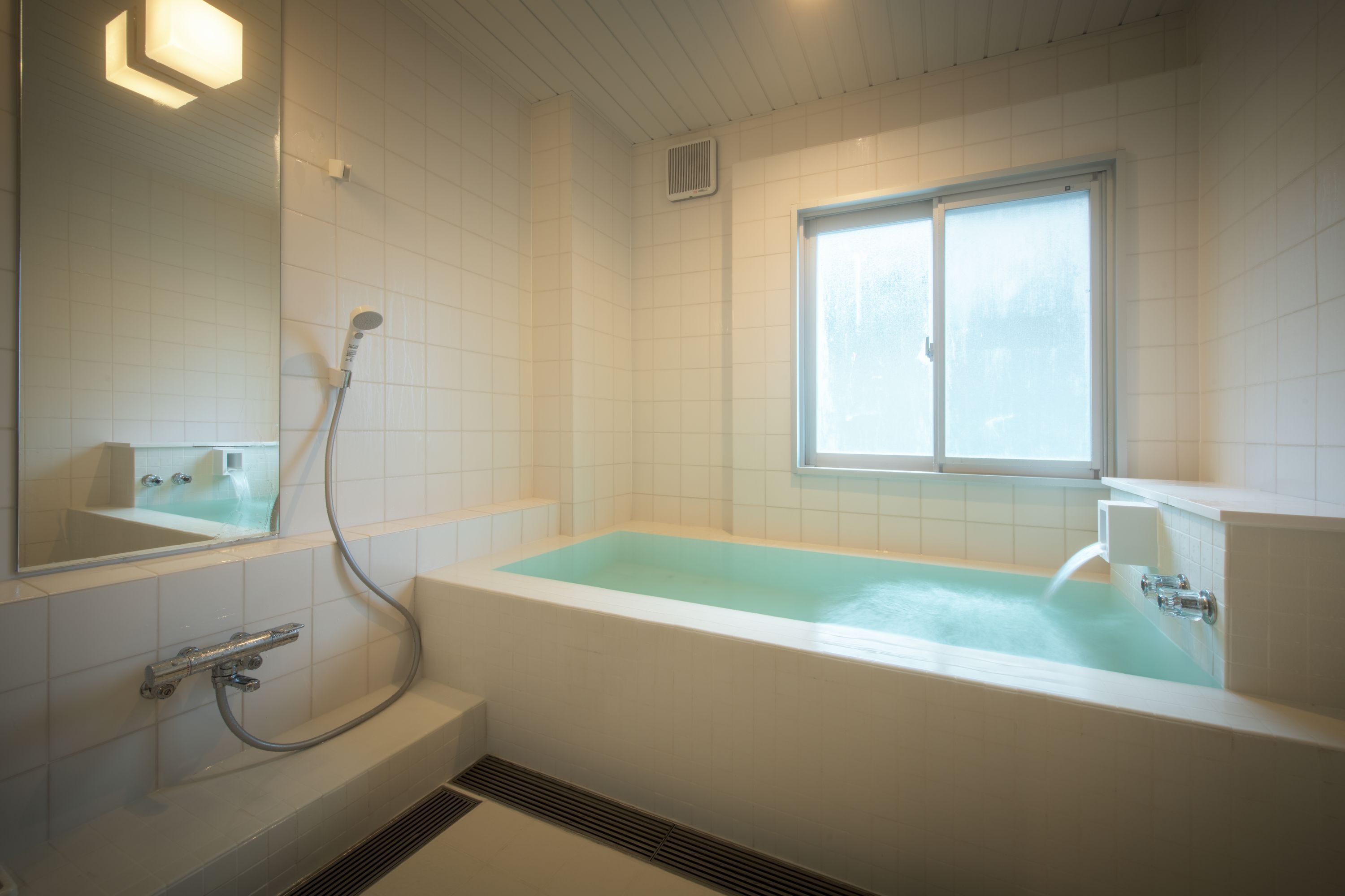 A modern bathroom with a freestanding bathtub, a showerhead, and a window providing natural light.