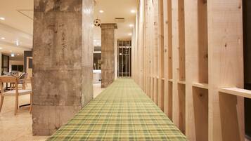 Un pasillo con alfombra a cuadros, paneles de madera y un pilar de concreto con escritura.