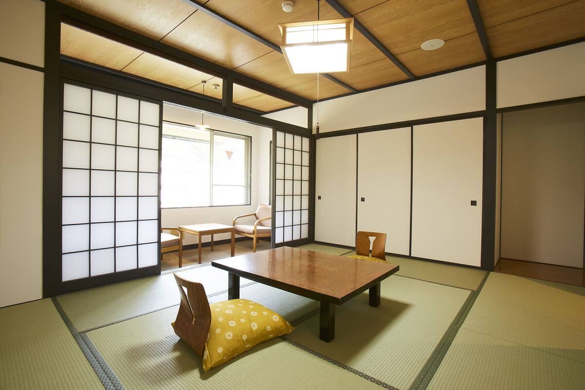 Ein traditioneller japanischer Raum mit Tatami-Böden, einem niedrigen Tisch und Schiebetüren.