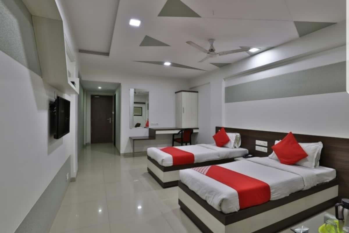 Quarto de hotel com duas camas, uma mesa e uma televisão.