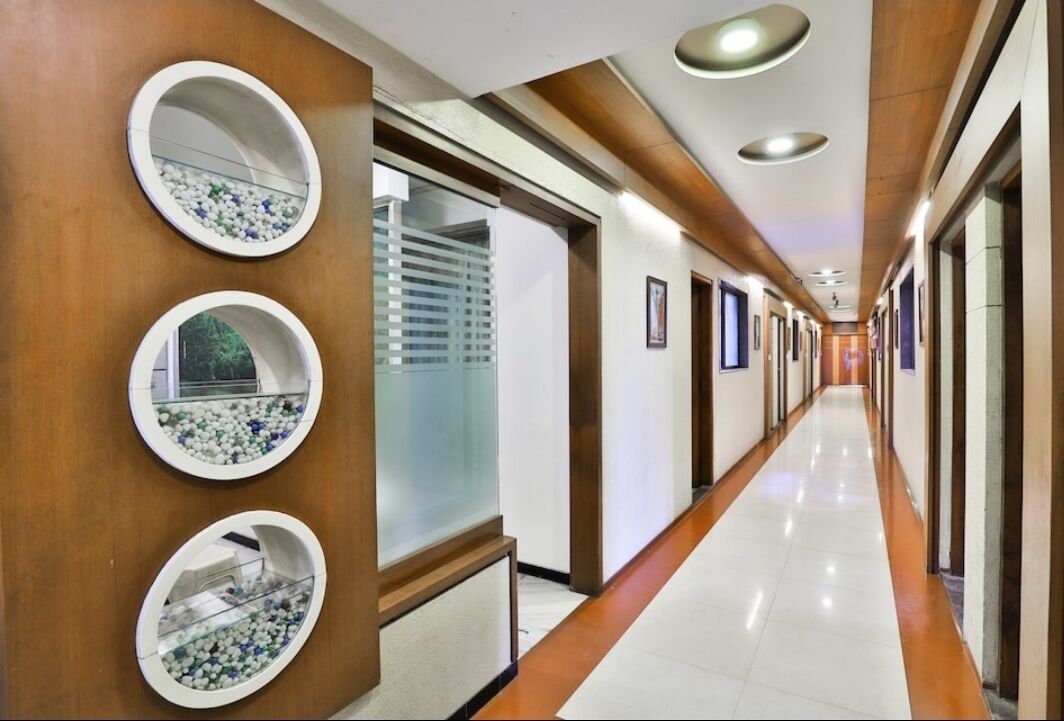 A hotel corridor with wooden paneling, circular mirrors, and a long, well-lit hallway.