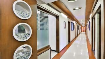 A hotel corridor with wooden paneling, circular mirrors, and a long, well-lit hallway.