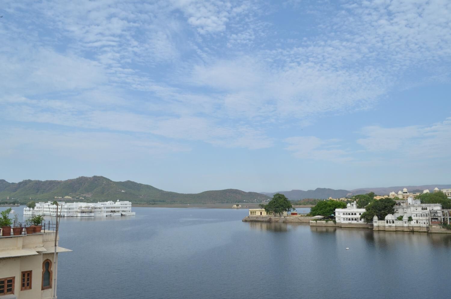 Um lago calmo com um barco branco atracado na margem, rodeado por edifícios com arquitetura tradicional.