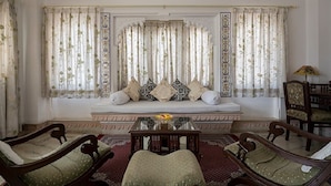 A traditional room with a sofa set, a wooden coffee table, and two armchairs. - Hotel Raj Niwas (Udaipur)