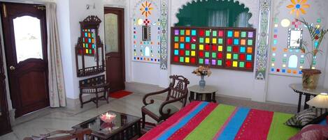 A traditional room with a bed, chairs, a small table, and a mirror.