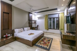 A modern bedroom with a large bed, a flat-screen TV, and a ceiling fan.