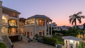 A large, multi-story building with a grand entrance, a spacious courtyard, and a well-maintained garden.