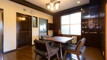 Un coin repas avec une table et des chaises en bois, un lustre et une vue sur l’extérieur grâce à une grande fenêtre.