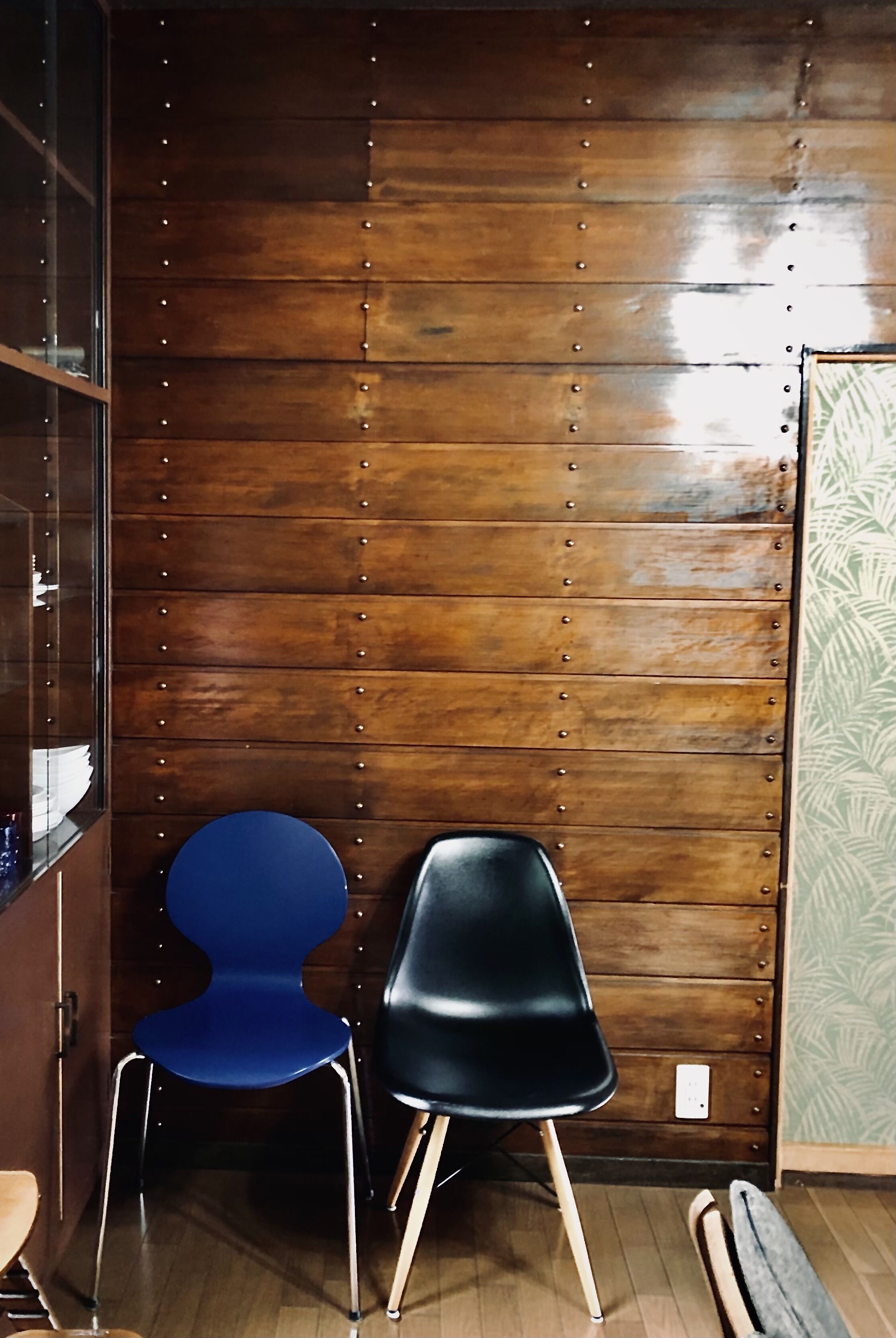 Una habitación con paredes de madera, dos sillas, piso de madera y una pared verde con diseño.