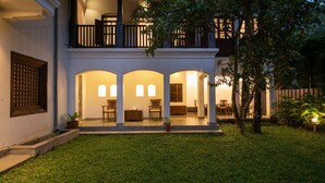 A two-story house with a covered patio area, multiple seating arrangements, and a well-maintained lawn.