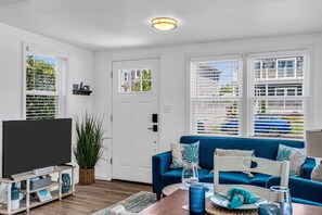 Una sala de estar con un televisor de pantalla plana, un sofá azul y una mesa de centro.