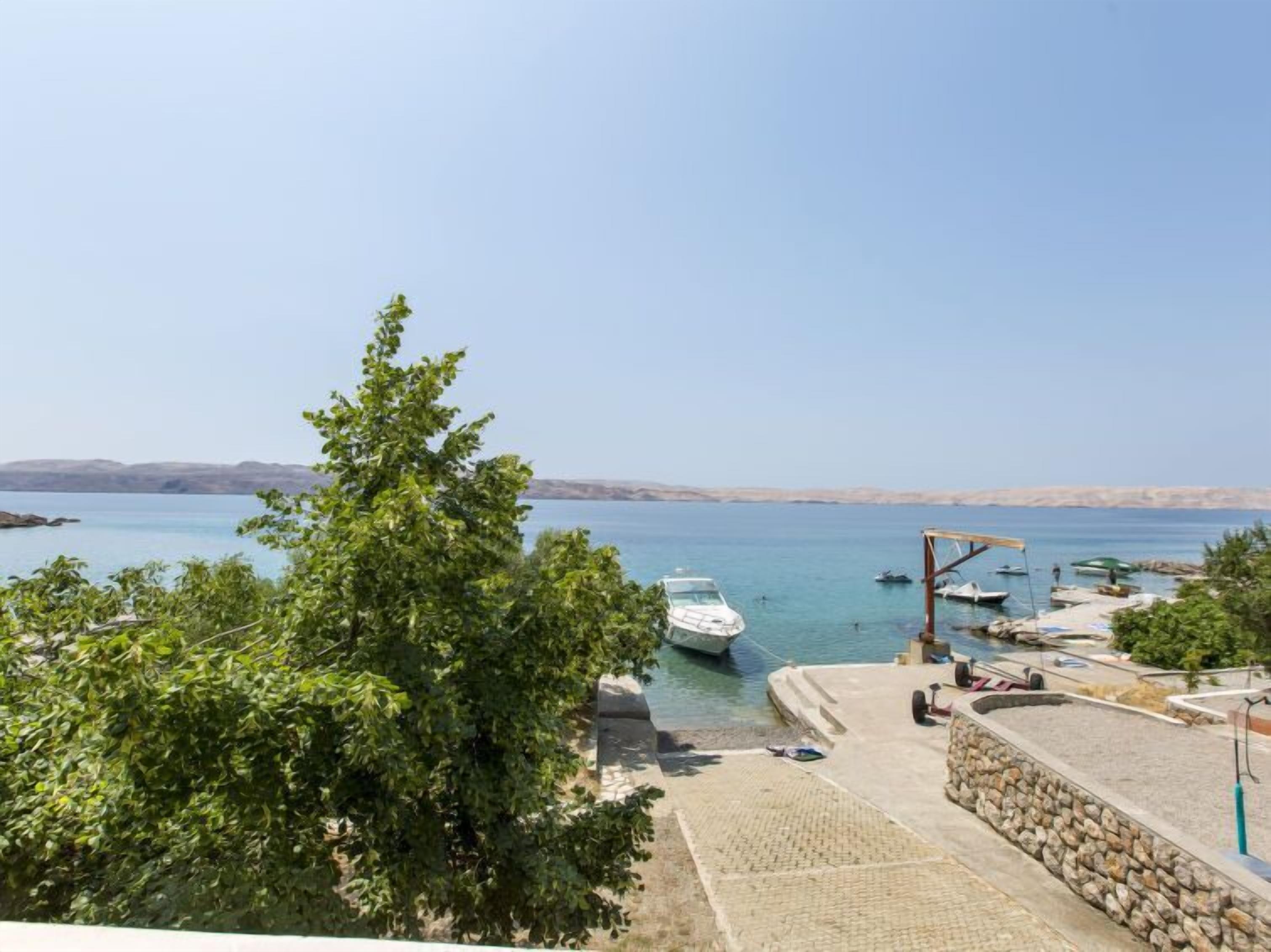 A coastal marina with boats, a stone wall, and a clear view of the sea.