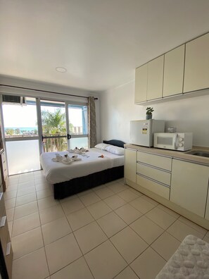 A hotel room with a bed, a kitchenette, and a balcony with a view of the ocean. - Town House Apartment Hotels Suva (Suva)