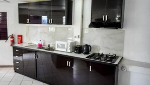 Une cuisine moderne avec des meubles de couleur noire, un four à micro-ondes, une bouilloire et une cuisinière à gaz.