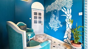 A hallway with teal chairs, a patterned floor, and a wall mural. - Ashapura Niwas by Vista Rooms (Jaipur)