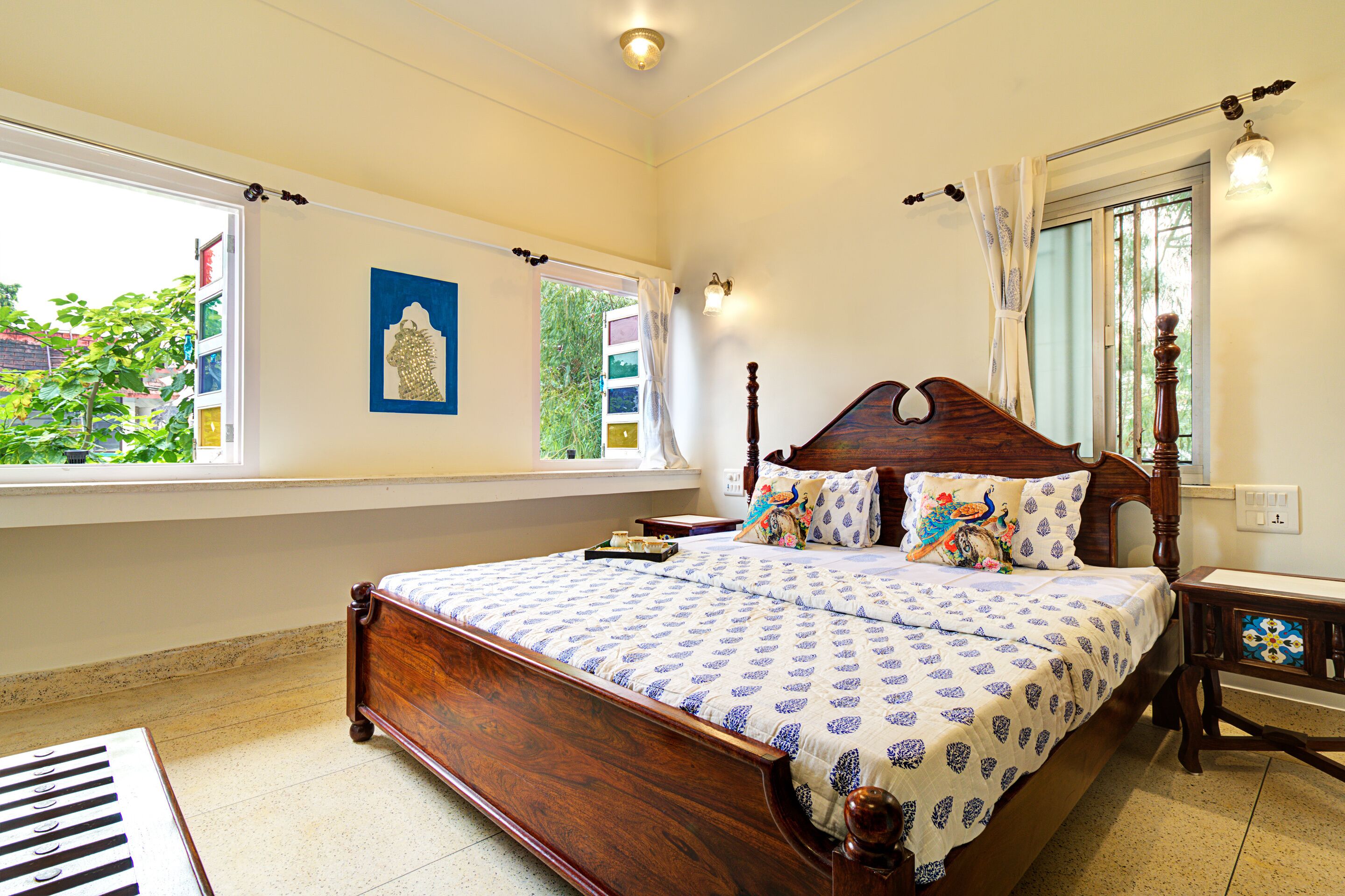 A bedroom with a large bed, a piano, and a window with a view of greenery.
