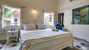 A bedroom with a bed, a nightstand, a window, and a door. - Ashapura Niwas by Vista Rooms (Jaipur)