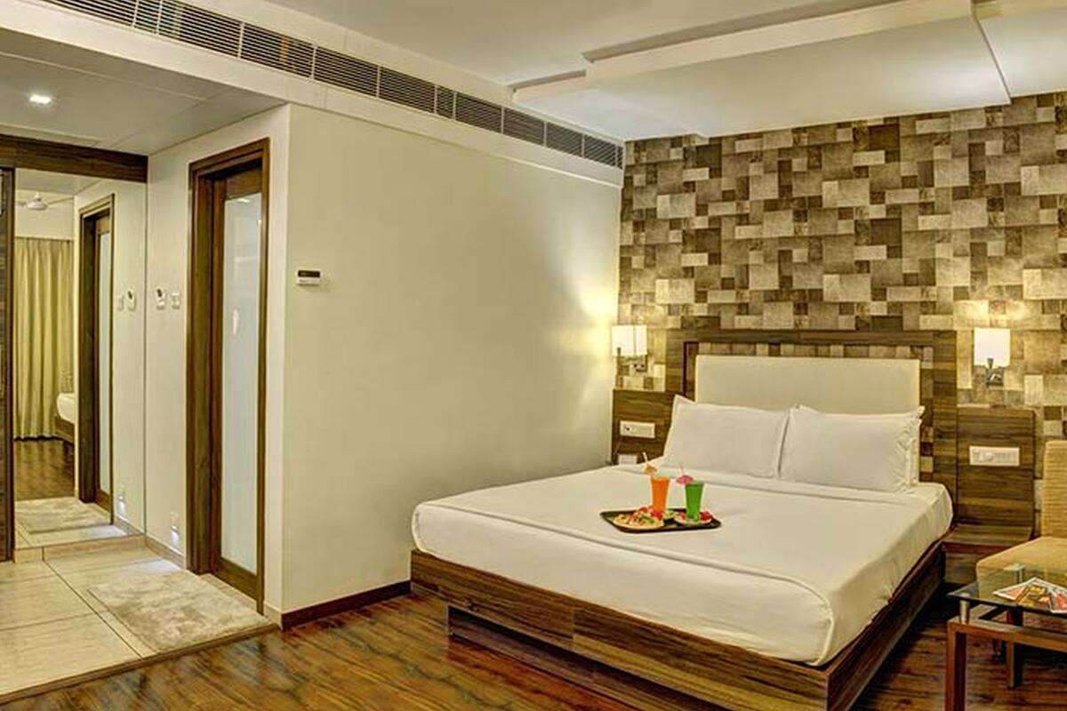 A hotel room with a large bed, a wooden headboard, a small side table, and a chair.