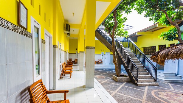 A corridor with benches, a staircase, and a tree. - OYO 1427 Azzahra Guest House Syariah (Mataram)