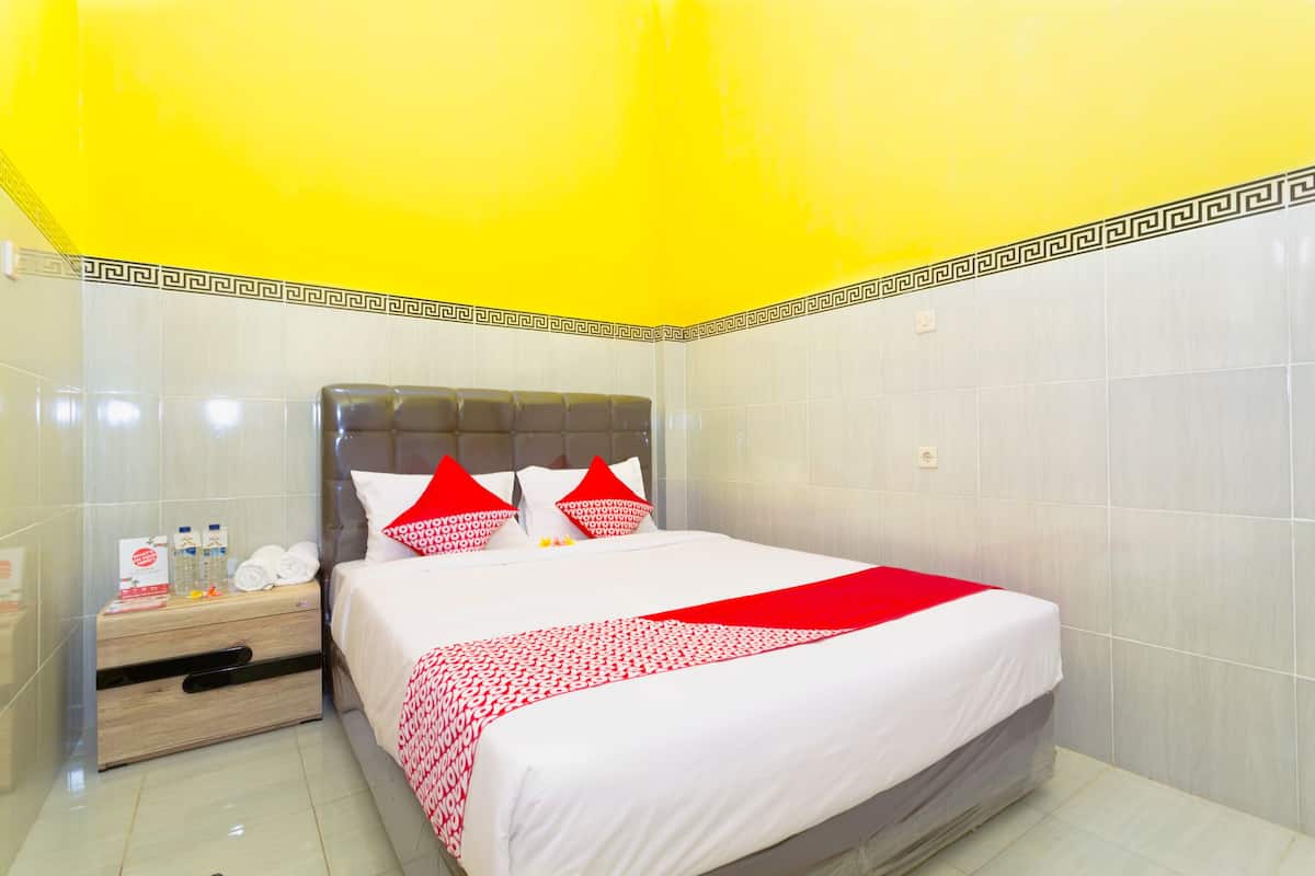 A hotel room with a bed, a nightstand, and a mirror.