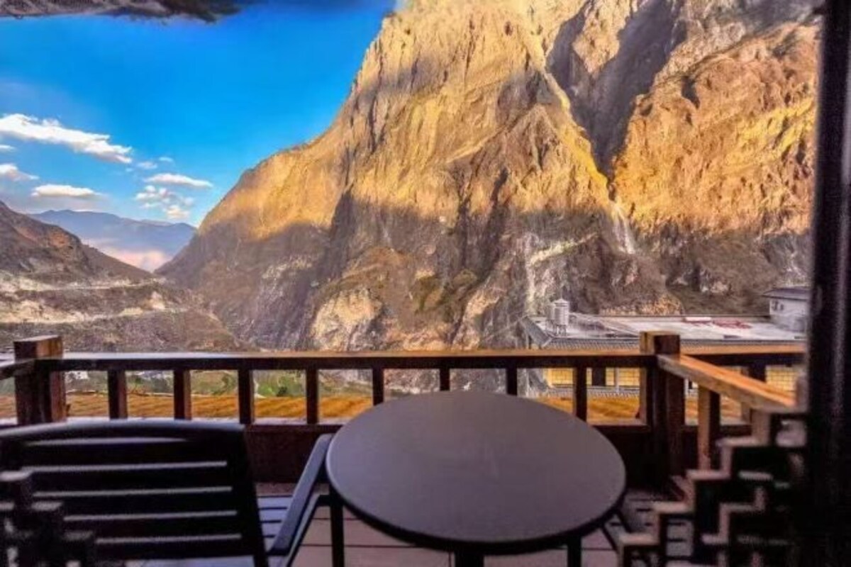 Eine Terrasse mit Blick auf eine gebirgige Landschaft, einem Tisch und Stühlen.