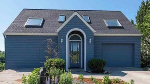 A two-story house with a dark blue exterior, a front entrance with an arched doorway, and a garage. - Kendall Yards Home - Stunning views, amazing downtown location (Spokane)